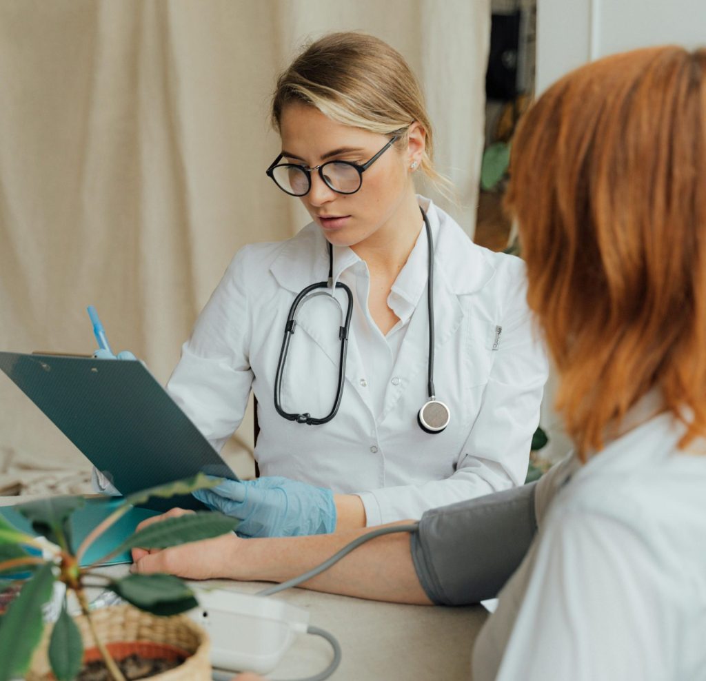 A female doctor checks a patient's blood pressure during a routine consultation in a clinic.